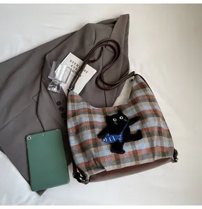 Detail der karierten Hobo-Tasche aus Wolle mit schwarzer Katzenstickerei und Ledergurt