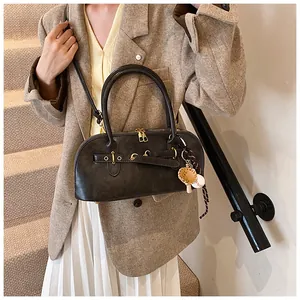 Detail of vintage gray leather shell bag with gold hardware and baseball charm