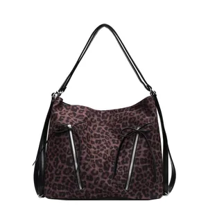 Detalle de bolso de leopardo con bolsillos dobles con cremallera y lazos de cinta negra