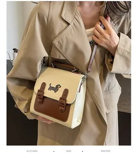Detailed view of beige vintage crossbody bag with dachshund embroidery and buckled straps