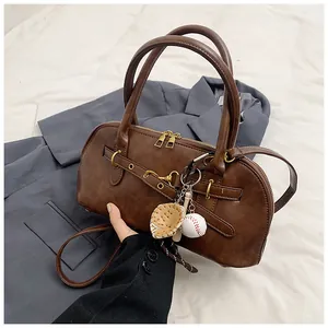 Detail of vintage brown shell bag with golden metal rings and unique baseball charm