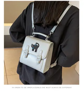 Close-up of light blue mini backpack with black cat embroidery and dual buckle straps