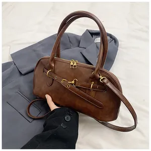 Detail view of vintage brown leather bag with dual gold zippers and sleek metal buckles