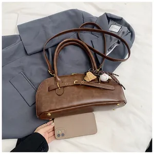 Detail view of brown shell bag showing matte leather texture and creative baseball charm