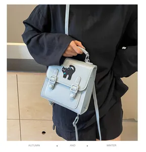 Close-up of light blue crossbody bag featuring cute cartoon cat embroidery and strap details