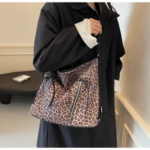 Bolso bandolera con estampado de leopardo y lazo negro lucido por una modelo en un interior
