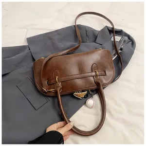 Close-up of retro dark brown leather handbag with baseball charm on a grey blazer
