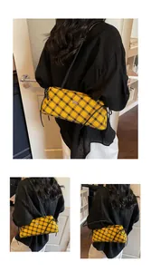 Close-up of yellow plaid baguette bag featuring a silver horse logo and black shoulder strap