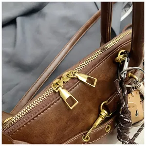 Detailed close-up of brown leather shell bag featuring gold zippers and hardware