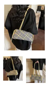 Detail of yellow and grey plaid baguette bag with leather handles and metallic logo