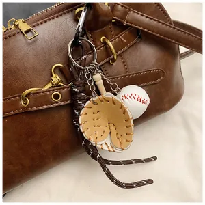 Detail of baseball keychain with mini glove and bat on a brown vintage leather bag