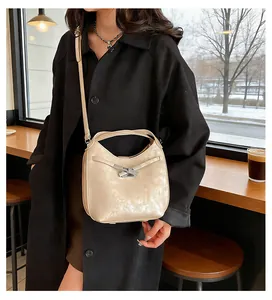 Detailed view of champagne leather bucket bag with elegant bow-shaped metal clasp