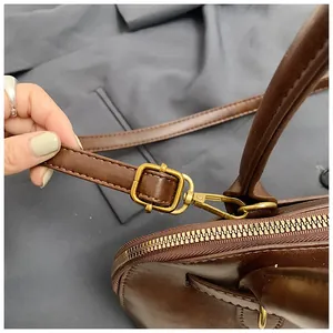 Detail of adjustable strap buckle and golden hardware on dark brown shell bag