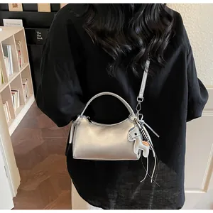Detail der silbernen Baguette-Tasche mit Rundgriff und Pferdeanhänger am Model