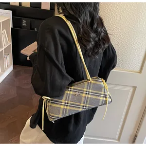 Detailed side view of a rectangular plaid shoulder bag with yellow strap on a model