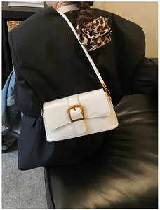 White faux leather baguette bag with gold buckle worn as a shoulder bag by model