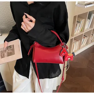 Detail der roten Baguette-Handtasche mit Pferdeanhänger in gemütlicher Atmosphäre