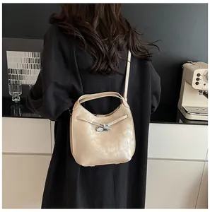 Detail of elegant beige bucket bag with silver knot buckle shown in a lifestyle setting