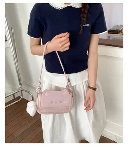 Detailed shot of pink cat-shaped shoulder bag with cute embroidery and plush paw charm