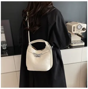 Chic cream bucket bag with silver criss-cross buckle shown in a stylish lifestyle setting