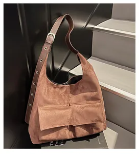 Detail of a brown suede Hobo bag with utility pockets and adjustable eyelet strap