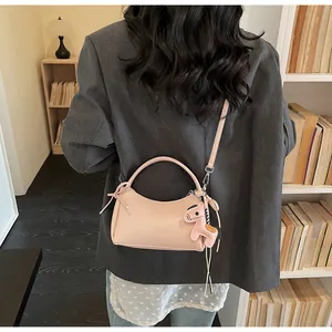 Modell mit rosa Leder-Halbmondtasche und Pferdeanhänger in einer Bibliotheks-Umgebung
