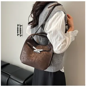 Detailed side view of a brown vintage leather bucket bag with metal buckle on a model