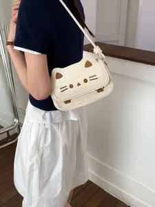 Sac bandoulière chic en forme de chat crème avec broderie porté par un mannequin en salle