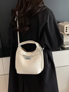 Chic cream leather bucket bag with silver metal buckle shown on a model's shoulder