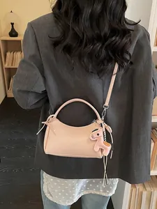 Rosa minimalistische Baguette-Tasche mit Pferdeanhänger, am Modell im Innenraum gezeigt