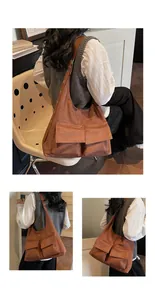 Detail view of brown suede tote bag featuring cargo flap pockets and metal eyelet strap