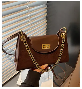 Detail of dark brown baguette bag with matte patchwork textures and golden metal clasp
