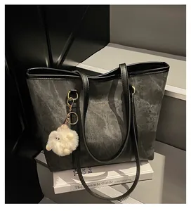 Detail of dark grey marble tote bag with black leather trim and cute plush sheep charm