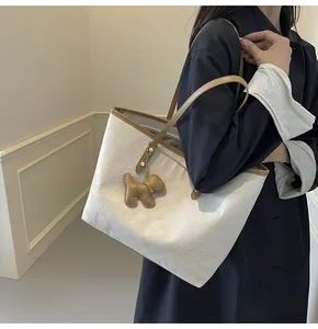 Detail of white tote bag with brown trim, geometric pattern and cute dog charm accessory