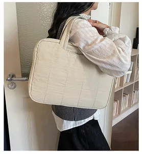 Detail of a large cream quilted shoulder bag showing the soft texture and carry handle