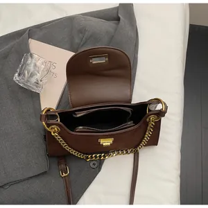 Detail view of the deep brown leather baguette bag with metal clasp and chain strap