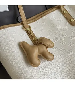 Detail of white tote bag with geometric patterns and a brown leather dog charm