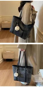 Macro detail of marble pattern tote bag featuring black handles and cute sheep charm pendant