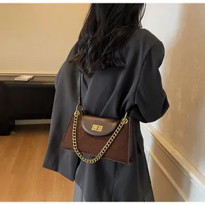 Detail of dark brown baguette bag with golden chain and metallic twist lock closure