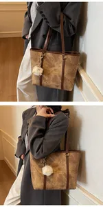 Close-up of brown tote bag with vintage marble texture and white fuzzy keychain detail