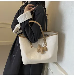 Detail of cream tote bag with embossed textures and a cute brown dog charm accessory
