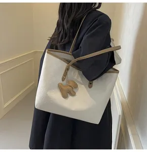 Close-up of white checkerboard tote bag with brown leather trim and cute puppy charm
