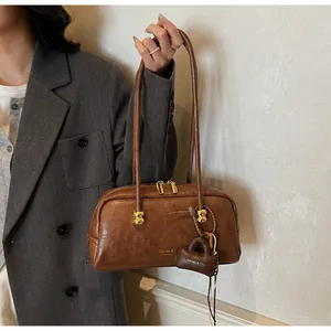 Detalle de bolso Boston de cuero marrón vintage con asas largas y remaches dorados