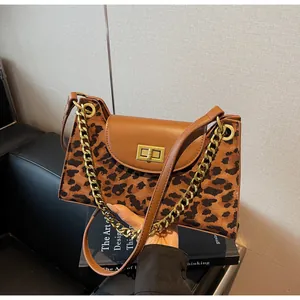 Detail of leopard print handbag featuring a gold turn-lock and chunky chain strap
