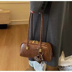 Detalle de un bolso Boston marrón con textura de cuero fino y herrajes de cuentas doradas