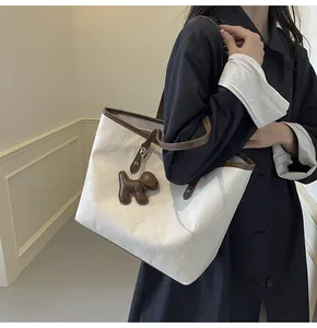 Detail of cream tote bag with checkerboard texture and brown dog charm accessory