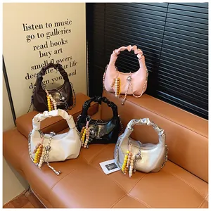 Close-up of pleated leather dumpling bags in five colors on a brown leather sofa