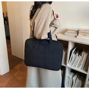 Détail du sac d'ordinateur matelassé noir avec poignée dans un bureau professionnel chic