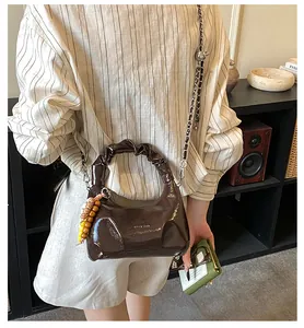 Detailed view of the dark brown glossy dumpling bag featuring a chic chain strap