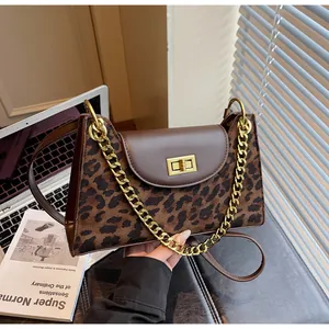 Detail of leopard print baguette bag with golden twist lock and dual chain straps